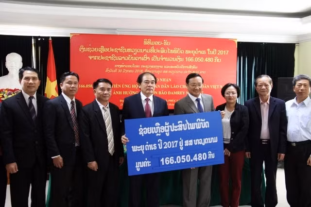 Đại sứ Nguyễn Bá Hùng (thứ tư từ phải sang) tiếp nhận tiền ủng hộ của người dân Lào do Bộ trưởng Khampheng Saysompheng trao, sáng 30-1. 