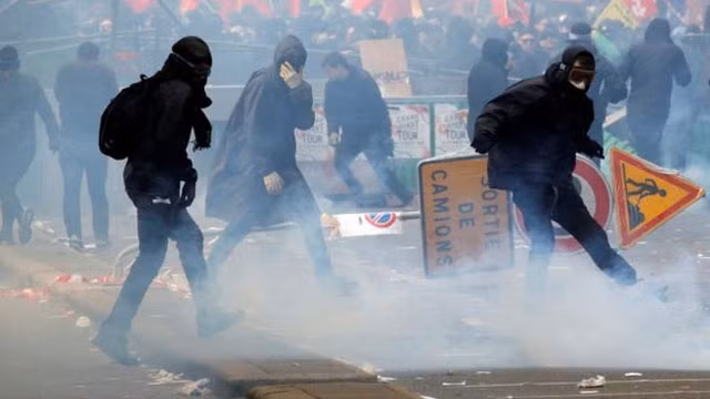 Nhóm bịt mặt trà trộn phá phách trên đường phố. Ảnh Reuters.