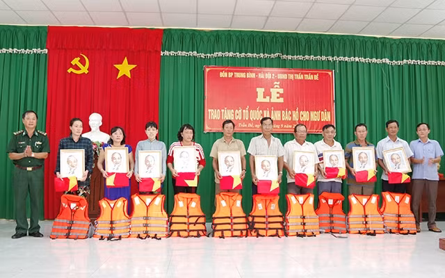 Lãnh đạo địa phương và BĐBP Sóc Trăng trao tặng cờ Tổ quốc, ảnh Bác Hồ và áo phao cho bà con ngư dân.