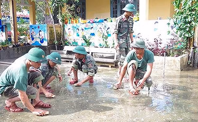 Cán bộ, chiến sĩ Bộ Chỉ huy Quân sự tỉnh Thừa Thiên-Huế tham gia dọn dẹp vệ sinh các trường học ở huyện Quảng Ðiền để học sinh sớm quay trở lại trường học. Ảnh: QUANG ÐẠO