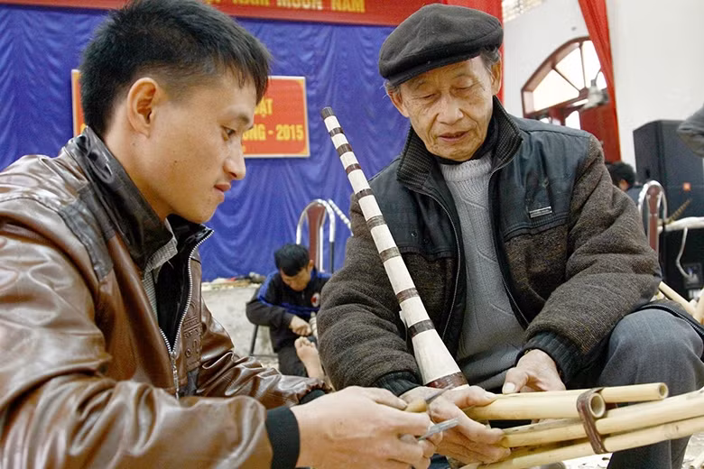 Nghệ nhân Ma Khái Sò (người bên phải), ở huyện Quản Bạ, hướng dẫn lớp trẻ thổi khèn Mông.