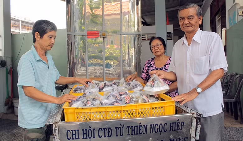 Ông Lê Tấn Ðức (người bên phải) phát cơm miễn phí cho người bệnh nghèo.