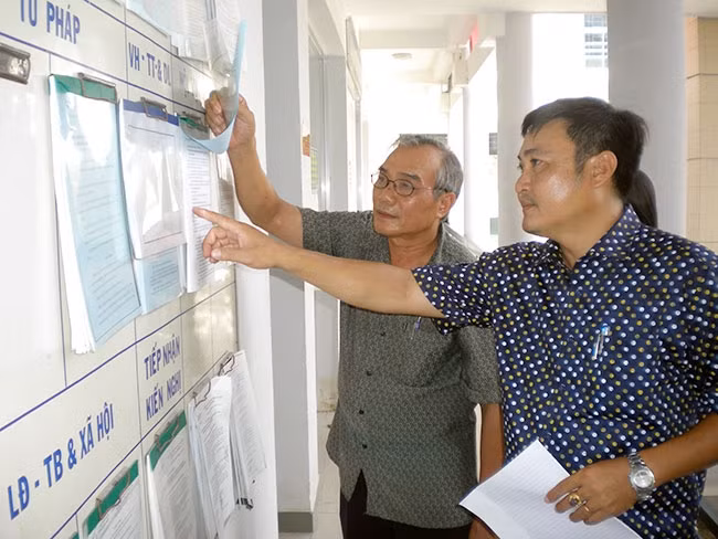 Quyền Chủ tịch UBND xã Vĩnh Lương (TP Nha Trang) Nguyễn Chánh Thức (bên phải), hướng dẫn thủ tục hành chính cho người dân.