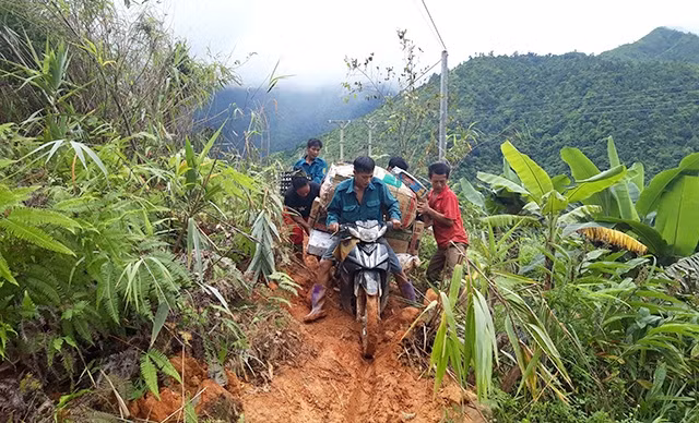 Người dân xã Pa Vệ Sủ (huyện Mường Tè) giúp nhau vượt qua các điểm sạt lở để đưa hàng hóa về bản.