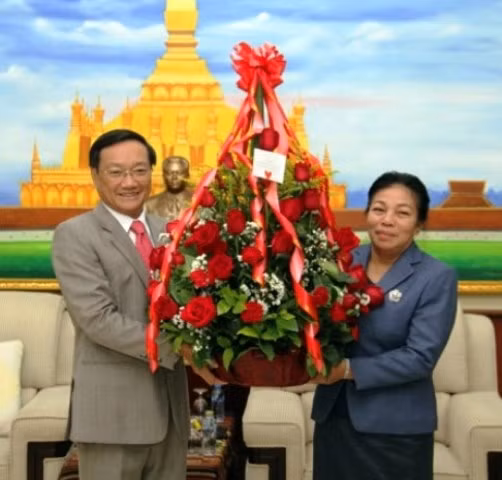 Đại sứ Nguyễn Bá Hùng (trái) chuyển lãng hoa tươi thắm đến đồng chí Sunthon Saynhachac, Trưởng Ban Đối ngoại T.Ư Đảng NDCM Lào.