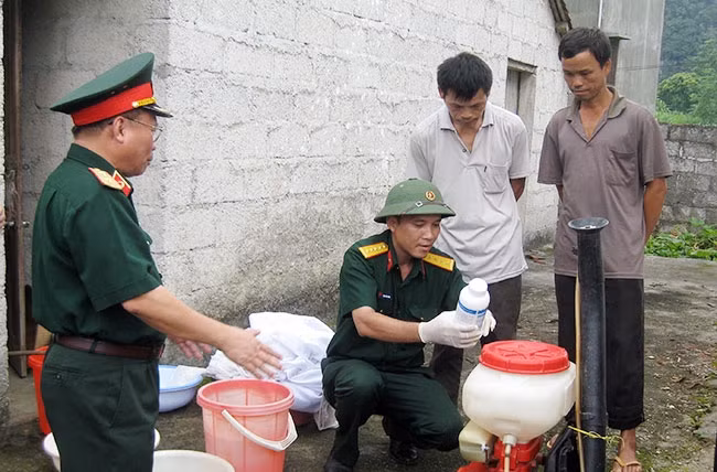 Cán bộ quân y hướng dẫn người dân pha hóa chất diệt côn trùng trong phòng, chống dịch bệnh.