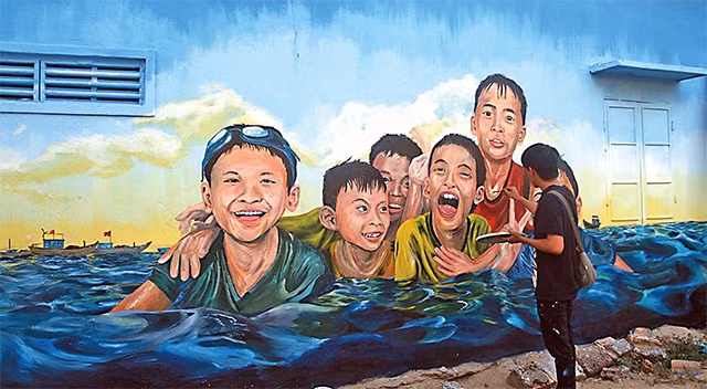 Tình nguyện viên thực hiện bích họa tại xã đảo Tam Hải, huyện Núi Thành, Quảng Nam. Ảnh: Kenh14.vn
