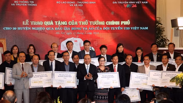 Thủ tướng Chính phủ Nguyễn Xuân Phúc trao kinh phí thu được từ đấu giá áo thi đấu, quả bóng của đội tuyển U23 Việt Nam cho đại diện 20 huyện nghèo.