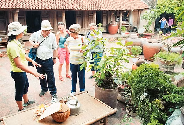 Khách du lịch nước ngoài tham quan không gian sinh hoạt tại làng cổ Ðường Lâm. Ảnh: VĂN PHÚC