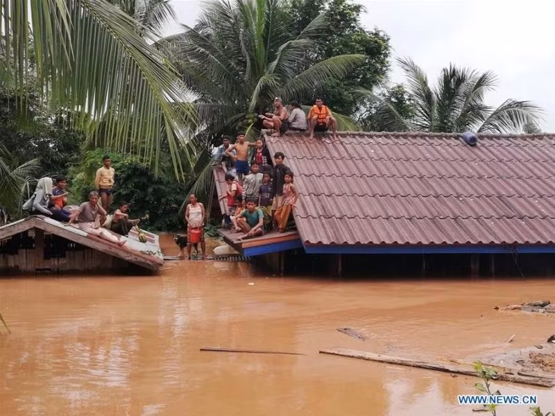 Người dân tại tỉnh Attapeu leo lên mái nhà để tránh nước lũ sau sự cố đập thủy điện. (Ảnh: Tân Hoa xã)