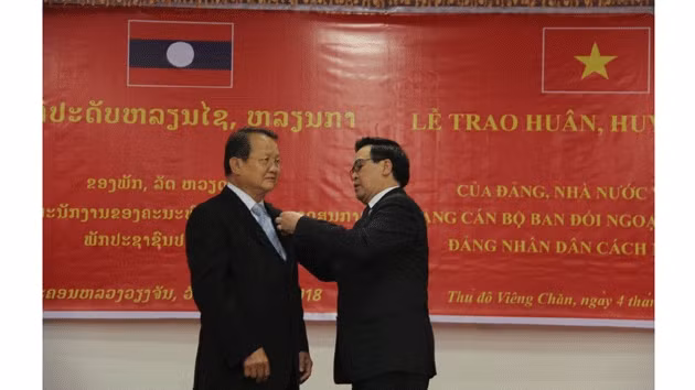 Đồng chí Hoàng Bình Quân (phải), Ủy viên T.Ư Đảng, Trưởng Ban Đối ngoại T.Ư Đảng gắn Huân chương Độc lập hạng Ba tặng đồng chí Somdee Bounkhum, Phó trưởng Ban Đối ngoại T.Ư Đảng NDCM Lào.