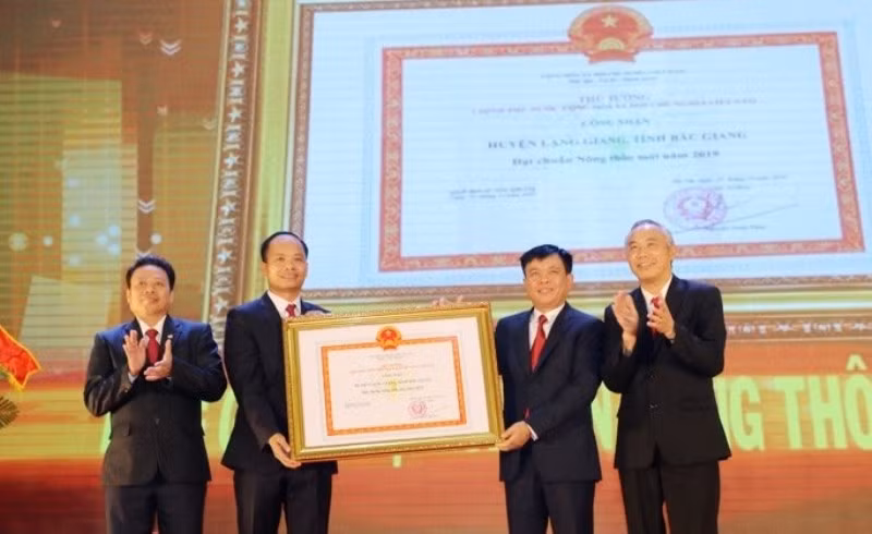 Đồng chí Phùng Đức Tiến, Thứ trưởng NN-PTNT (thứ nhất, bên phải) trao Quyết định công nhận đạt chuẩn NTM của Thủ tướng Chính Phủ cho huyện Lạng Giang.