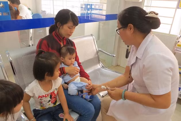 Người dân TP Buôn Ma Thuột đưa con em mình đến Trung tâm Y tế dự phòng tỉnh Đác Lắc tiêm vắc-xin phòng chống viêm não Nhật Bản B. 