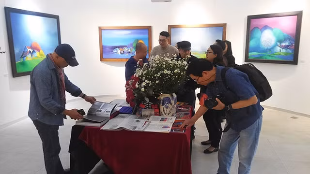 Khách tham quan tại triển lãm và xem sách của họa sĩ.