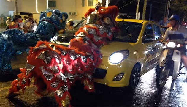 Một đội lân ngang nhiên chặn ô-tô xin tiền trên đường Phan Bội Châu, TP Buôn Ma Thuột.