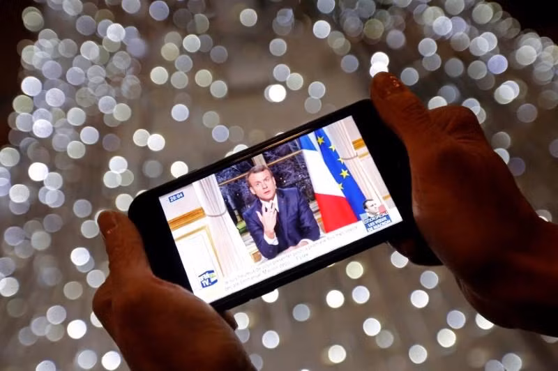 Người dân theo dõi bài phát biểu đón năm mới 2018 của Tổng thống Macron. (Ảnh: Reuters)