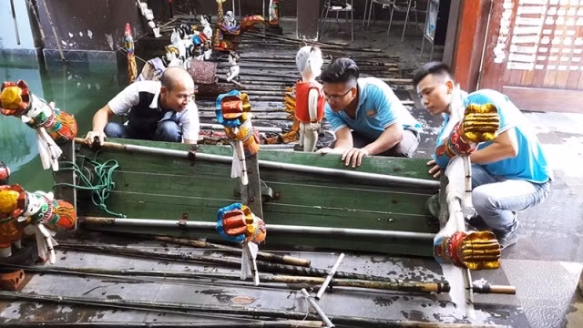 Anh Tâm (ngoài cùng bên trái) cùng anh em nhà hát rối nước Ánh Trăng làm công tác bảo trì.