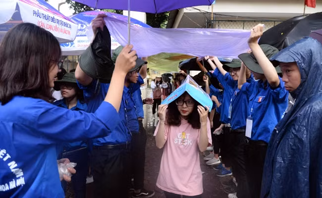 Thanh niên tình nguyện hỗ trợ thí sinh ra về sau buổi thi tổ hợp Khoa học xã hội tại điểm thi Trường THPT Việt Đức (Hà Nội). Ảnh: THỦY NGUYÊN