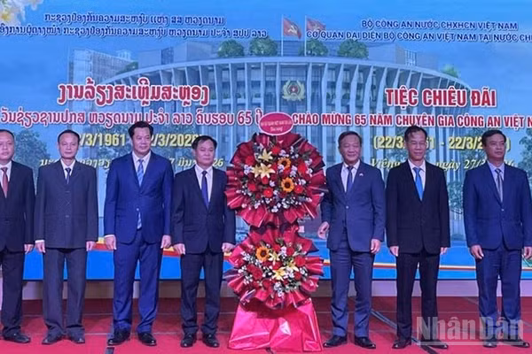 Đại sứ Nguyễn Minh Tâm (thứ 3 từ phải qua) tặng hoa chúc mừng đội ngũ Chuyên gia Công an Việt Nam tại Lào. (Ảnh: DUY TOÀN)