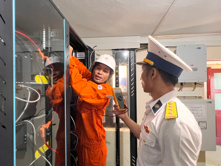 Kỹ sư Công ty Điện lực Ninh Thuận và cán bộ đảo Đá Đông A phối hợp kiểm tra hệ thống ắc quy trữ điện trên đảo.