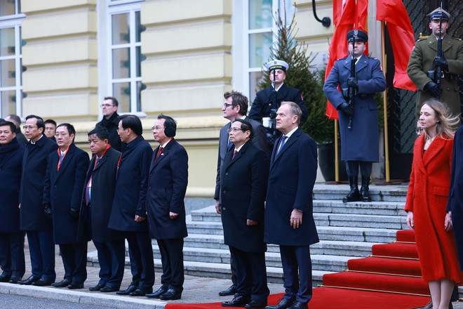 Thủ tướng Phạm Minh Chính và Thủ tướng Cộng hòa Ba Lan Donald Tusk nghe quân nhạc cử Quốc thiều hai nước. (Ảnh: Dương Giang/TTXVN)