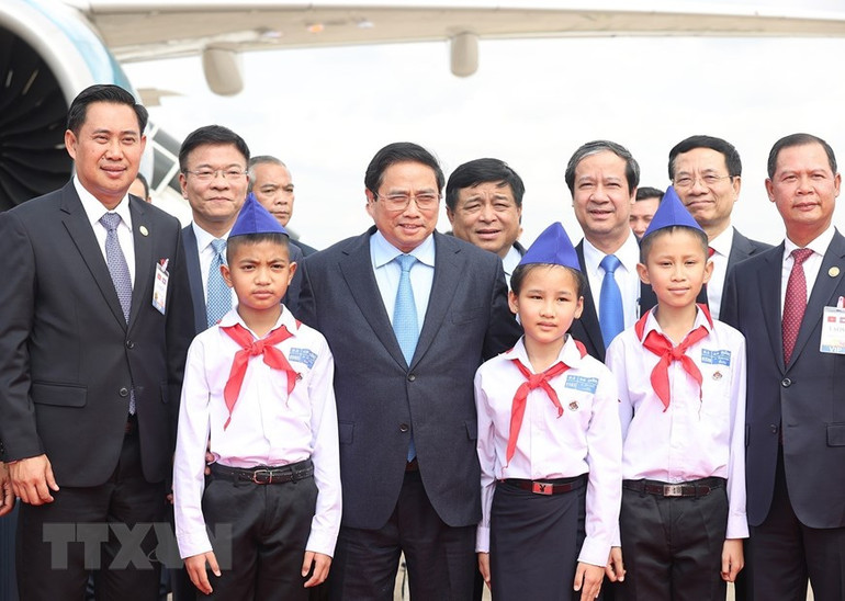 Thủ tướng Phạm Minh Chính chụp ảnh với các cháu thiếu nhi tại lễ tiễn ở sân bay Quốc tế Wattay, thủ đô Vientiane. (Ảnh: Dương Giang/TTXVN)