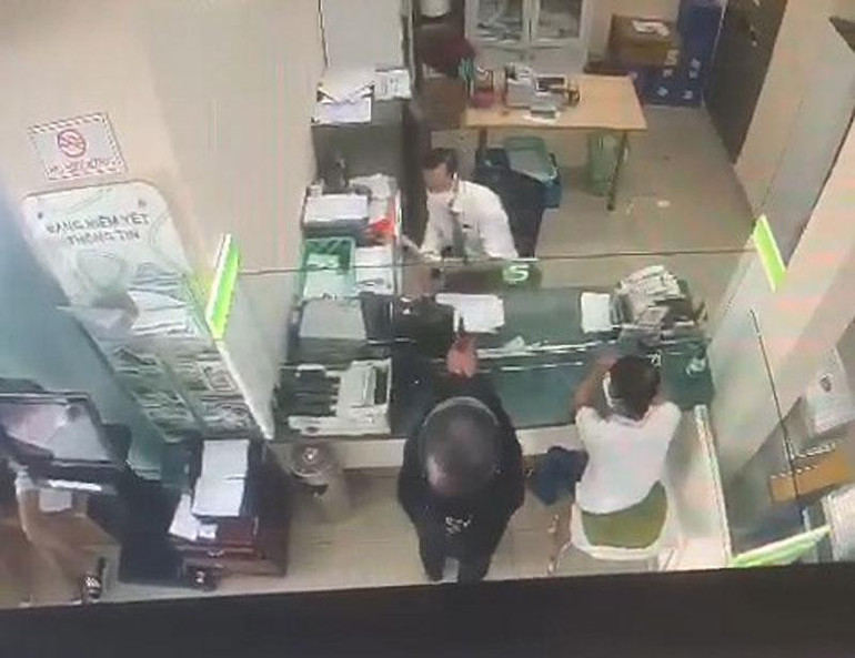 Đối tượng giơ súng uy hiếp nhân viên phòng giao dịch. (Ảnh cắt từ clip)