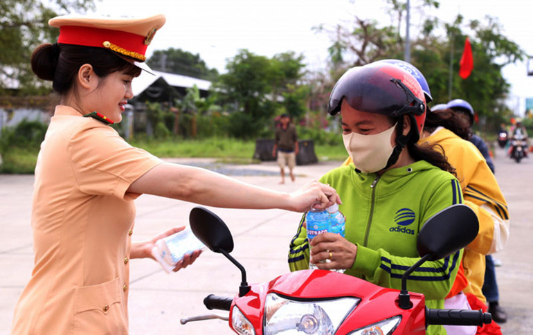 Nữ chiến sĩ Cảnh sát giao thông Công an tỉnh Sóc Trăng hỗ trợ nước uống cho người dân tham gia giao thông.