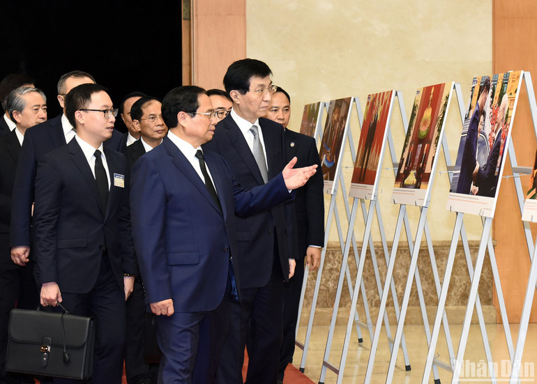 Thủ tướng Phạm Minh Chính giới thiệu với Chủ tịch Chính hiệp Toàn quốc Trung Quốc Vương Hộ Ninh một số hình ảnh về hoạt động đối ngoại của Tổng Bí thư Nguyễn Phú Trọng.
