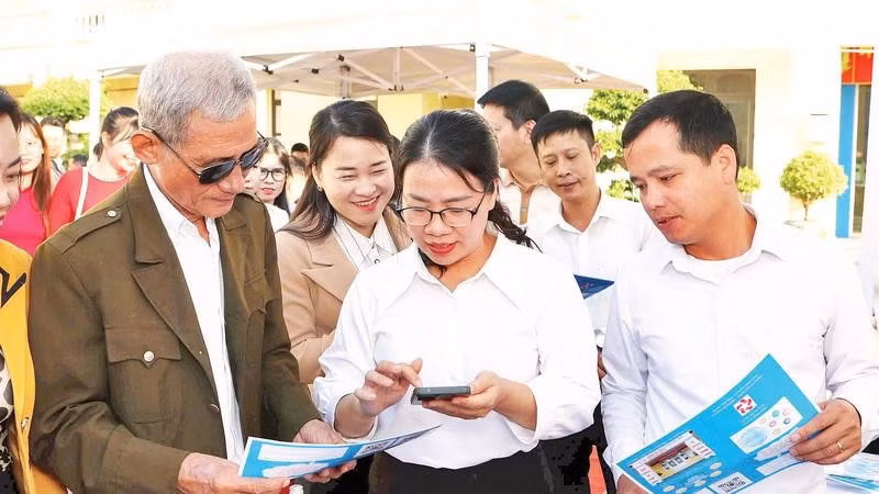 Cán bộ phường An Phong hướng dẫn người dân lấy số thứ tự giải quyết thủ tục hành chính trên VNeID.