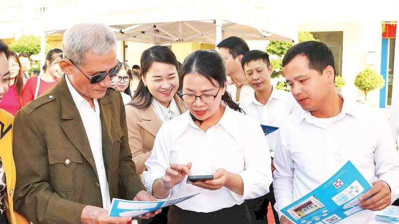 Cán bộ phường An Phong hướng dẫn người dân lấy số thứ tự giải quyết thủ tục hành chính trên VNeID.