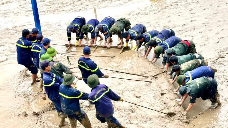 Các đồng chí công an tỉnh Quảng Trị hợp sức cào bùn ở sân trường tại thành phố Huế. (Ảnh: VGP)