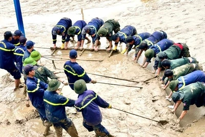 Các đồng chí công an tỉnh Quảng Trị hợp sức cào bùn ở sân trường tại thành phố Huế. (Ảnh: VGP)