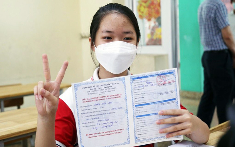Trẻ được tiêm và nhận chứng nhận tiêm vắc-xin phòng Covid-19.