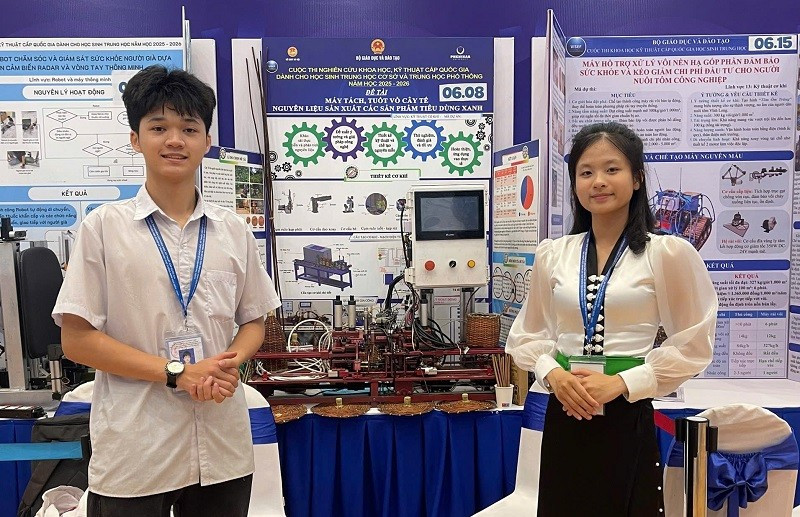 Em Nguyễn Tiến Mạnh và Dương Thị Duyên bên "Máy tách, tuốt vỏ cây tế - nguyên liệu sản xuất sản phẩm tiêu dùng xanh" được trao giải Tư tại Cuộc thi. 