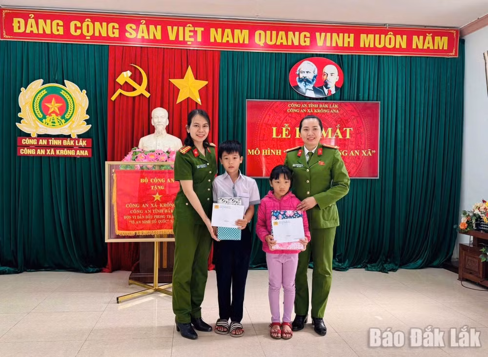 Đại diện Công an xã Krông Ana tặng quà cho con nuôi Đặng Hải Đăng và Hoàng Bảo Ngọc.