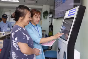 Cán bộ Bệnh viện Đống Đa (Hà Nội) hướng dẫn người dân sử dụng công nghệ số trong việc đăng ký khám, chữa bệnh. (Ảnh HUY HOÀNG)
