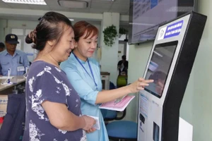 Cán bộ Bệnh viện Đống Đa (Hà Nội) hướng dẫn người dân sử dụng công nghệ số trong việc đăng ký khám, chữa bệnh. (Ảnh HUY HOÀNG)