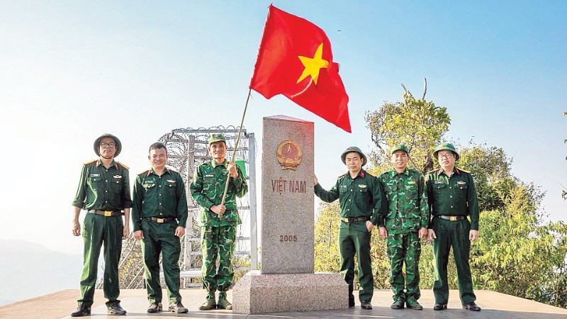 Thượng úy Lục Vĩnh Lương (người cầm cờ) cùng tác giả và đoàn công tác tại Cột mốc số 0 - Ngã ba biên giới A Pa Chải - Cực tây Tổ quốc.