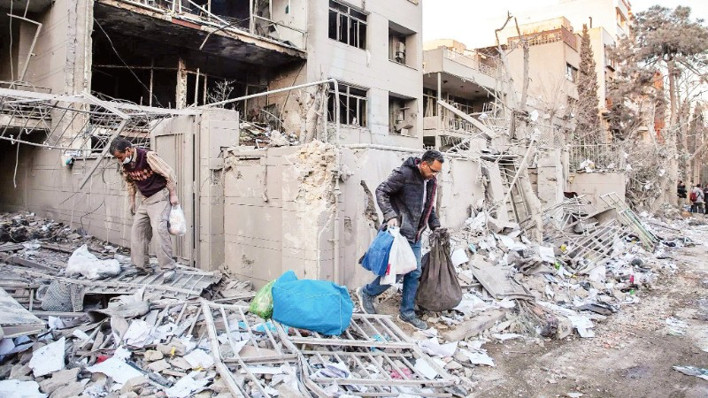 Người dân thu dọn đống đổ nát sau một vụ không kích tại Iran. (Ảnh: THE NEW YORK TIMES)