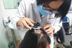 Bác sĩ kiểm tra tình trạng rụng tóc của bệnh nhân.