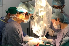 Ê-kíp mổ thực hiện vi phẫu nối lại ngón tay cho người bệnh với kính hiển vi.