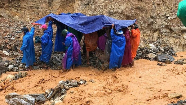 Lực lượng dân quân thường trực xã Trà Leng cùng người nhà dùng võng để khiêng bệnh nhân qua khu vực sạt lở.