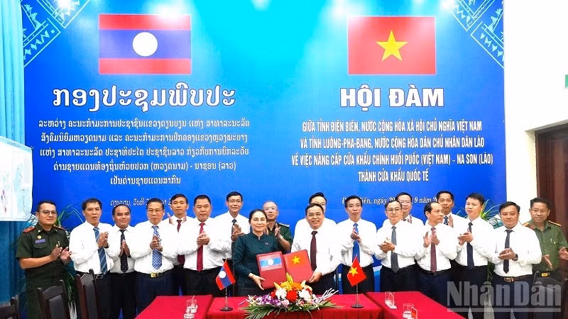 Hai đồng chí Trưởng đoàn trao biên bản hội đàm ký kết về việc thống nhất báo cáo cấp có thẩm quyền nâng cấp cặp cửa khẩu chính Huổi Puốc (Việt Nam)-Na Son (Lào) thành cửa khẩu quốc tế. (Ảnh: LÊ LAN)