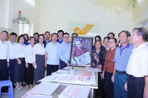 Đồng chí Lê Quốc Minh trao tặng bức tranh Bác Hồ đọc Báo Nhân Dân cho cán bộ, Đảng viên, nhân dân xã Tân Hưng tại điểm bưu điện văn hóa xã Tân Hưng (Hưng Yên).