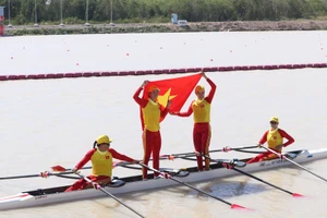 Các tay chèo Việt Nam tự hào giương cao quốc kỳ sau khi cán đích về nhất. 
