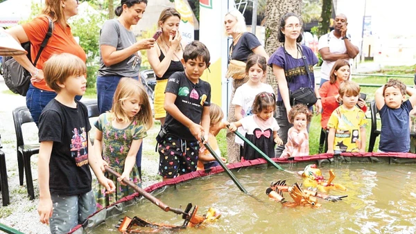 Du khách quốc tế “nhí” thử điều khiển rối nước trong một buổi biểu diễn do Đông Đô tổ chức. (Ảnh: NVCC)