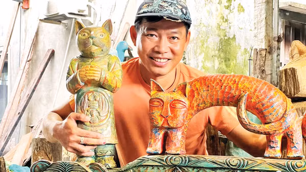 Anh Lê Ngọc Thuận bên một số tác phẩm từ củi lũ. (Ảnh: NVCC)