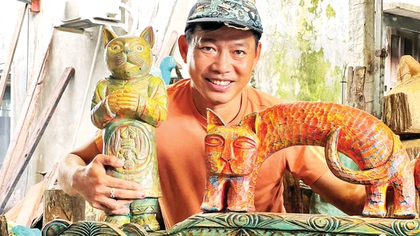 Anh Lê Ngọc Thuận bên một số tác phẩm từ củi lũ. (Ảnh: NVCC)