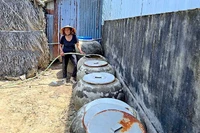 Bà Lý Thị Xuyên bơm nước dưới ao chứa vào lu, xử lý lại bằng phèn chua để có nước tắm, giặt.